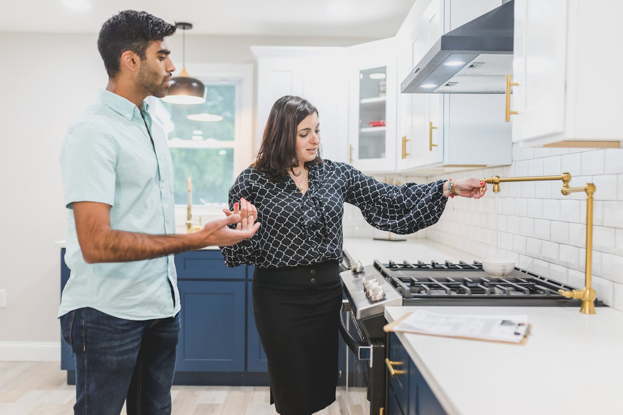 The Art of Drawing Readers In: Your attractive post title goes here Real estate agent showing a modern kitchen interior with brass fixtures to a client.